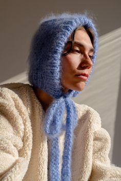 The Brushed Mohair Bonnet is your fluffy new best friend. Hand-knit in our signature super soft mohair, it delivers warmth and comfort while offering a playful twist to classic headwear. Its long, textured ribbons allow you to tie it either at the front or at the back, giving you styling flexibility to suit any look or mood. Wear it snug for full coverage or draped loosely as a hood for a more relaxed vibe. Handcrafted in Greece. DETAILS * Super soft, premium quality Italian mohair * 60% kid moh Hood Scarf Knitting Pattern, Mohair Projects, Hijab Editorial, Knitting Bonnet, Balaclava Knitted, Bonnet Outfit, Mohair Shrug, Mohair Bonnet, Balaclava Knit