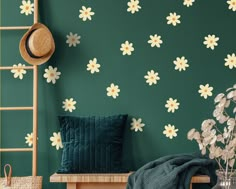 a green wall with white daisies on it and a ladder in the foreground