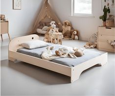 a child's bed with stuffed animals on it in a room that has white walls