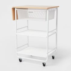 a white cart with a wooden top and two baskets on the bottom, sitting against a white background