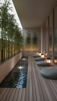 an indoor swimming pool with bamboo trees and lights on the wall next to it, surrounded by wooden flooring