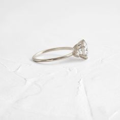 Round cut focal diamond of your choice. Need help choosing a diamond? Our Customer Care team is right here. This design features an open basket setting with six prongs on a delicate 1.2mm band—available in platinum or 14k solid yellow, white or rose gold. The band is accented by two (2.5mm) round white diamonds, one on each side of the focal stone. All accent diamonds are SI clarity and G+ color. We handcraft each piece with responsibly sourced 14k gold and ethically sourced stones. Minimalist Moissanite Diamond Cut Rings, Minimalist Moissanite Wedding Ring, Delicate Silver Diamond Ring With Prong Setting, Minimalist Marquise Cut Vvs Diamond Ring, Delicate Diamond Promise Ring With Center Stone, Delicate Cubic Zirconia Diamond Ring With Prong Setting, Minimalist Marquise Cut Diamond Ring With Vvs Clarity, Delicate Cubic Zirconia Solitaire Diamond Ring, Vvs Clarity Marquise Cut Minimalist Diamond Ring