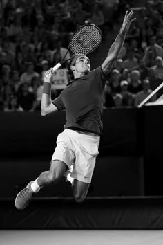 a man jumping in the air to hit a tennis ball with his racquet