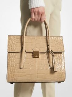 “The Campbell bag is the ultimate in timeless, pragmatic chic. It’s a bag that works for a life on the go, with everything from the most casual to the most glamorous,” says Michael Kors. This quintessential satchel is finely crafted in Italy from crocodile-embossed leather with minimal hardware and a suede-lined interior, while a push-lock fastening reveals a pocketed interior to neatly store a day’s worth of essentials. Let it add a sense of refined elegance to the season’s softly tailored dres Luxury Calf Leather Work Bag, Luxury Calf Leather Bag For Work, Luxury Workwear Bags In Textured Leather, Designer Textured Leather Bag For Work, Luxury Workwear Satchel, Luxury Bag With Palladium Hardware For Work, Luxury Bags With Palladium Hardware For Work, Designer Work Bag With Silver-tone Hardware, Luxury Textured Leather Shopping Bag