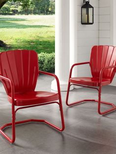 two red chairs sitting next to each other on top of a cement floor in front of a tree