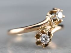 a gold ring with two white diamonds on the top and one diamond in the middle