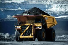 a large yellow dump truck driving down a road