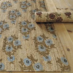 an area rug with blue flowers on it laying on the floor next to a wood floor