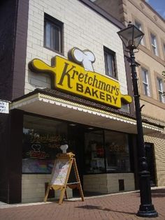 a sign for a bakery on the side of a building with a light pole in front of it