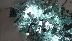 a pile of broken glass sitting on top of a white floor next to a wall