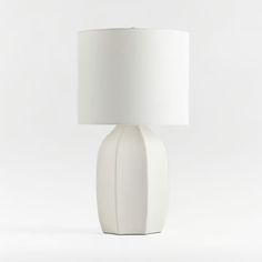 a white table lamp with a white shade on the base and a white fabric lampshade