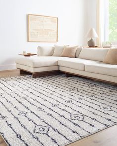 a living room with a white couch and large rug on top of the wooden floor