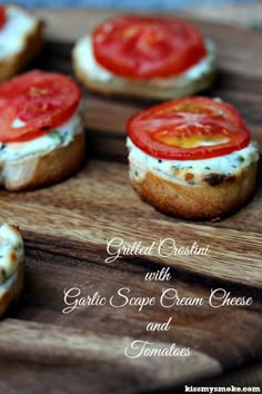 small crackers with cream cheese and tomatoes on them sitting on a wooden cutting board