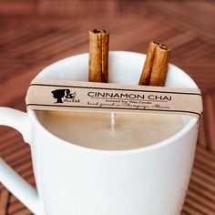 cinnamon chai sticks in a white cup on a wooden table with a label that says cinnamon chai