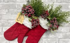 two christmas stockings with flowers and greenery hanging from them