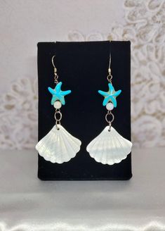 Add a touch of seaside charm to your look with these stunning Turquoise and white shell earrings featuring a whimsical starfish accent. These fun and stylish earrings are perfect for beach days, summer outings, or adding a pop of color to your everyday ensemble. Handcrafted with care, these earrings are sure to make a splash wherever you go. WHAT'S IN THE BOX: 1 pair of earrings. Any other items shown in picture are for staging and to show scale and are not included with purchase. Thank you for visiting my shop! White Starfish Pendant Ocean-inspired Jewelry, White Ocean-inspired Jewelry With Starfish Charm, Ocean-inspired White Jewelry With Starfish Charm, Ocean-inspired Drop Earrings With Starfish Charm, Nickel-free Starfish Earrings Ocean-inspired, White Starfish Earrings For Beach, White Ocean-inspired Dangle Jewelry, White Starfish Charm Earrings, Ocean-inspired Starfish Charm Dangle Earrings