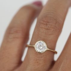 a woman's hand with a diamond ring on top of her finger, showing the center stone