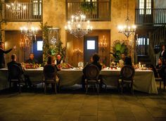 a group of people sitting around a table in front of a building with chandeliers