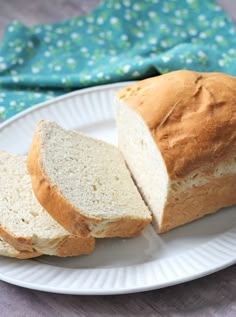 a white plate topped with sliced bread on top of a wooden table next to a blue napkin