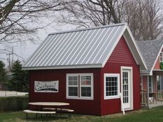 a small red building with a picnic table in front of it and an image of the outside