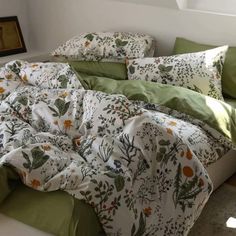 an unmade bed with green and white sheets, pillows and blankets on top of it