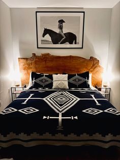 a bed with a black and white comforter in a bedroom next to a wooden headboard