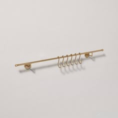 a gold coat rack with five hooks on each side and four clips hanging from the back