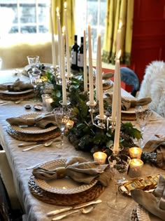 the table is set with candles, plates and napkins for dinner guests to enjoy