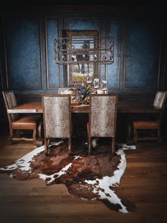 a dining room table with chairs and a cowhide rug