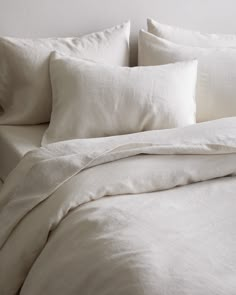 an unmade bed with white linens and pillows