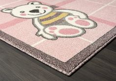 a pink rug with a teddy bear on the front and back side, sitting on top of a wooden floor