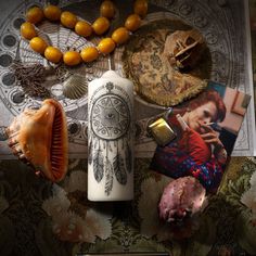 an assortment of items including a candle, pictures and beads on a floral tablecloth