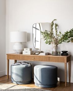 a wooden table topped with two stools next to a mirror and plant on top of it