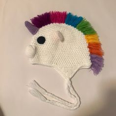 a crocheted unicorn hat with multi - colored hair on it's brim