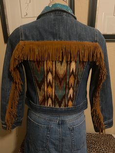 the back of a jean jacket with fringes on it's shoulders and an animal print