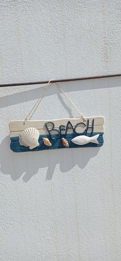 a sign hanging on the side of a building with sea shells and seashells