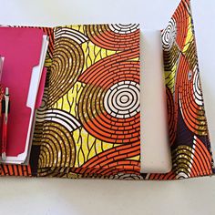 These document holders are savant mixture of African fabric and woven natural raffia fibers. This briefcase reveals an erosion of creativity, a mix of traditional and modernism. The inside of these briefcases is recovered with Ankara and is big enough to hold anything, from pens, documents to even a computer ( max size 13" x 9"). Unique pieces. Great conversation starter. Perfect for conference, school or as gifts. The Ankara print on the inside is the same for all briefcases. However, no two br Multicolor Rectangular Organizers With Pen Holders, Multicolor Rectangular Organizer With Pen Holders, Notes Creative, Closure Design, Ankara Print, Diy Notebook, Woven Raffia, Printed Jewelry, Document Holder