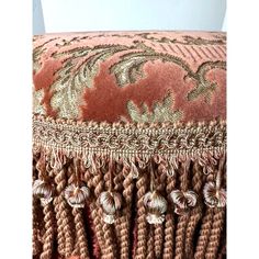 a pink and gold cushion with tassels on it