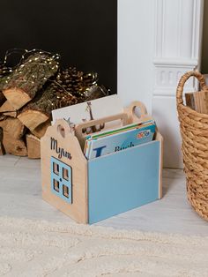 there is a wooden toy house next to a pile of books on the floor in front of a fireplace