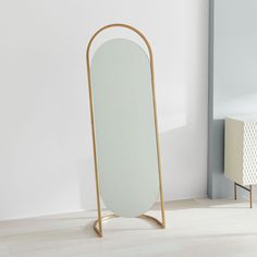 a mirror sitting on top of a wooden stand next to a white cabinet and wall