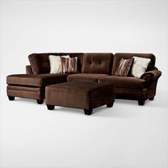 a brown couch and ottoman with pillows on it