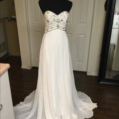 a white wedding dress on display in front of a door with a mannequin