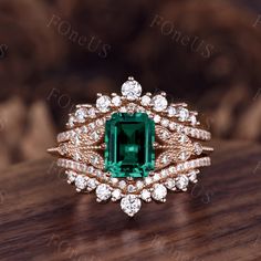 an emerald and diamond ring on top of a wooden table