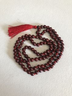 The beads of this mala are 100 % authentic and original. Tibetan / Mahayana style mala. Can be worn as a necklace or a wrap bracelet. Mala is made in traditional way with knots between the beads. Total beads 108+1 There are two kinds of sandalwood Red ( Rakta ) and white (Shweta). Rosaries of red sandalwood are useful for propitiating the goddess whereas white are useful for the gods. Red sandalwood is the symbol of Brahma and blessed by Lakshmi. It enlightens the super consciousness, provides i Red Gemstone Beaded Necklaces For Meditation, Red Beaded Necklace With 108 Beads For Meditation, Red Spiritual Necklace With 108 Beads, Red Necklaces With Round Beads For Meditation, Handmade Red Mala For Healing, Hand-strung Red Mala As A Gift, Red Hand-strung Mala As Gift, Red Gemstone Beads Mala As Gift, Red Mala With Gemstone Beads As Gift