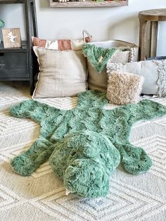 there is a green turtle rug on the floor next to pillows and other things in front of it