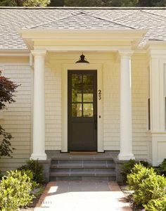 a white house with columns and a black door