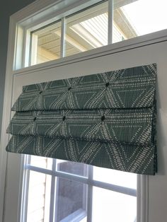 a window with a green and white patterned roman blind in front of the windowsill