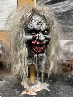 a creepy doll with white hair and blood dripping from it's eyes is on display