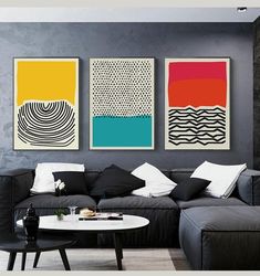 three paintings hang on the wall above a couch in a living room with black furniture