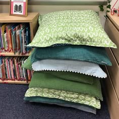 four pillows stacked on top of each other in front of a book shelf filled with books